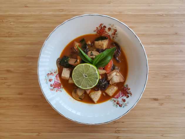 Peanut ramen soup in a bowl topped with lime and basil