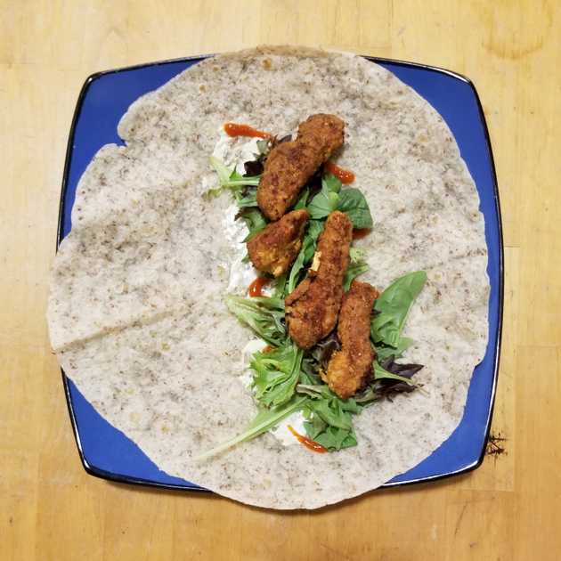 fried chicken, lettuce, and sauce in a flour tortilla wrap